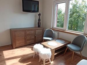 een woonkamer met een tafel en twee stoelen en een televisie bij Apartament Nad lipami in Hajnówka