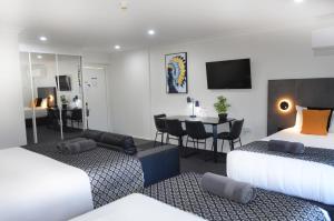 a hotel room with two beds and a dining room at Orana Motel in Dubbo