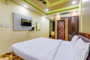 1 dormitorio con 1 cama blanca y TV en FabHotel GMC Grand, en Lucknow