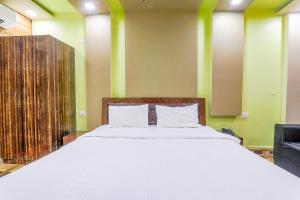1 dormitorio con 1 cama blanca grande y paredes verdes en FabHotel GMC Grand, en Lucknow