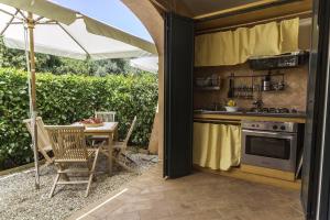 eine Außenküche mit einem Tisch und einem Sonnenschirm in der Unterkunft Residence Torre Delle Viole in Marina di Camerota