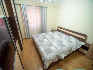 a bedroom with a bed with a checkered blanket at L&R Modern Apartment in Oţelu Roşu