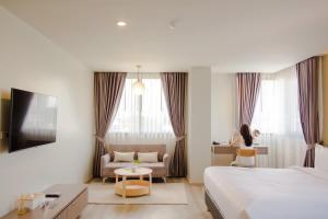 una habitación de hotel con una cama y una mujer sentada en una silla en The Rise Suites Hotel, Chiang Mai - SHA Extra Plus, en Chiang Mai