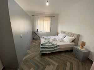 Daily Apartment Tirana في تيرانا: غرفة نوم بيضاء بها سرير ونافذة
