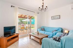 een woonkamer met een blauwe bank en een tv bij Son Ganxo ii in Cala Murada