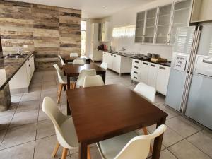 a kitchen with white cabinets and tables and white chairs at Avonlea Guesthouse in Polokwane