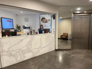 a woman is standing behind a counter in a lobby at APX World Square in Sydney