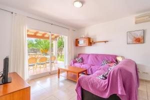 ein Wohnzimmer mit einem lila Sofa und einem Tisch in der Unterkunft Son Ganxo iii in Cala Murada