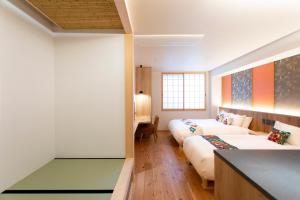 a hotel room with two beds and a desk at Hotel Kanazawa Zoushi in Kanazawa