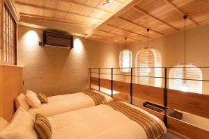 Hotel Kanazawa Zoushi في كانازاوا: سريرين في غرفة بها نافذتين