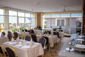 a restaurant with white tables and chairs and windows at Kilimanjaro Snow Peak Hotel in Himo