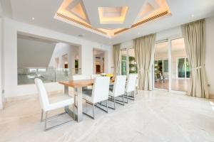uma sala de jantar com uma mesa de madeira e cadeiras brancas em Ultra Luxurious 9BR Villa in Emirates Hills by Deluxe Holiday Homes no Dubai