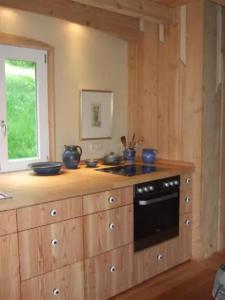 a kitchen with wooden cabinets and a black oven at Sonniges-naturnahes-Schwarzwald-Ferienhaeuschen in Welschensteinach