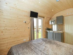 sypialnia w drewnianym domku z łóżkiem i kuchnią w obiekcie Beulah w mieście Axbridge