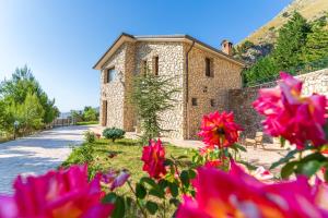 博格圖的住宿－Villa Romitello con Piscina Total Relax，一座石头建筑,前面有粉红色的花朵