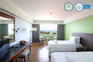 a hotel room with two beds and a television at Hua Hin Grand Hotel and Plaza - SHA Extra Plus in Hua Hin