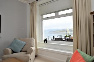 a living room with a chair and a large window at Bute View in Kames