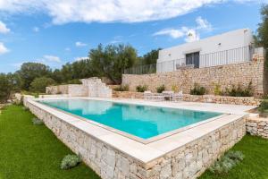 una piscina con un muro in pietra intorno a una casa di Villa degli Ulivi con piscina by Wonderful Italy a Ostuni