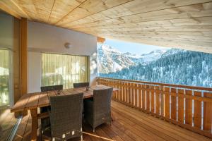 a wooden table and chairs on a balcony with mountains at Juggasunna in Arosa