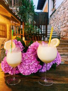 Sirviella的住宿－Posada El Pareón，坐在桌子上,一边用鲜花一边喝杯装的两杯鸡尾酒