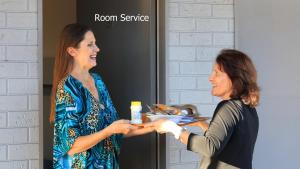 two women shaking hands in front of a room service sign at Motel 707 in Emerald