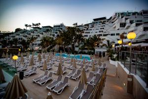 un grupo de sillas de césped y sombrillas en el balcón en Hotel Altamar, en Puerto Rico de Gran Canaria