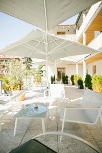 une terrasse avec des chaises blanches et un parasol dans l'établissement Apartmenthotel Oberstdorf, à Oberstdorf