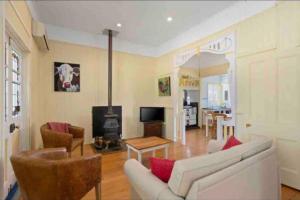 ein Wohnzimmer mit einer weißen Couch und einem Kamin in der Unterkunft Montrose Farm Stay - Charming 2 bedroom cottage in Goomburra