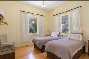 zwei Betten in einem Zimmer mit zwei Fenstern in der Unterkunft Montrose Farm Stay - Charming 2 bedroom cottage in Goomburra + 19 Fotos