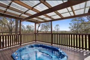 ein Whirlpool im Freien auf einer Terrasse mit Pergola in der Unterkunft Montrose Farm Stay - Charming 2 bedroom cottage in Goomburra