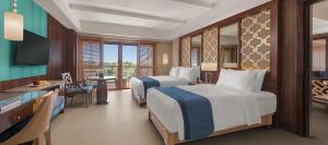 a hotel room with two beds and a desk at Henann Resort Alona Beach in Panglao