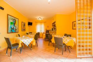 een eetkamer met tafels en stoelen en gele muren bij Bonsai B&B Alghero in Santa Maria la Palma