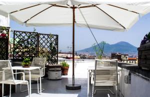 eine Terrasse mit Stühlen und einem Sonnenschirm auf einem Dach in der Unterkunft Taggarb in Neapel