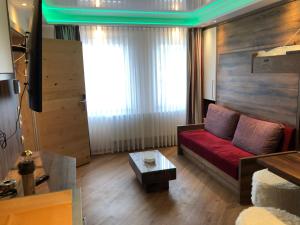 ein Wohnzimmer mit einem roten Sofa und einem Tisch in der Unterkunft Hotel Sperling mit E-Ladestation in Speyer