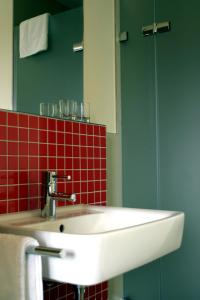 シュヴェービッシュ・ハルにあるLandhaus Rössleの白いシンクと赤いタイルのバスルーム