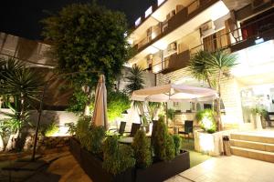 an outdoor patio with an umbrella and tables and chairs at Galini Palace in Athens