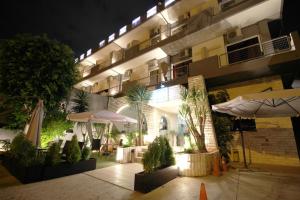 a hotel at night with umbrellas and plants in a courtyard at Galini Palace in Athens