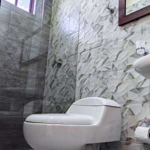 uma casa de banho com um WC branco e um chuveiro em Hotel Las Mercedes Airport-Quito em Tababela