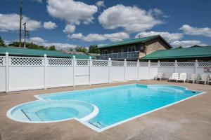 a swimming pool in a yard with a white fence at Howard Johnson by Wyndham Gananoque in Gananoque