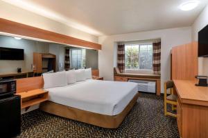 um quarto de hotel com uma cama grande e uma televisão em Microtel Inn & Suites by Wyndham Salt Lake City Airport em Salt Lake City