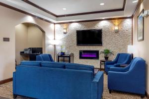 Comfort Inn Near UNT في دينتون: غرفة معيشة مع أرائك زرقاء وتلفزيون بشاشة مسطحة