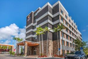 a building with palm trees in front of it at Comfort Suites Fort Lauderdale Airport & Cruise Port in Dania Beach