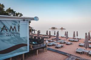 a beach with umbrellas and chairs and the water at Hotel AMI Budva Petrovac in Petrovac na Moru