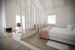 a white bedroom with a bed and a window at Casas da Lupa in Zambujeira do Mar