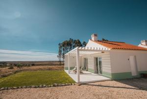 uma pequena casa branca com um alpendre em Casas da Lupa na Zambujeira do Mar