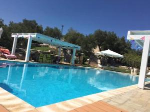 a large blue swimming pool with a pavilion at Casetta Letizia in Ostuni