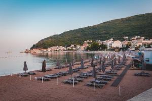 a group of chairs and umbrellas on a beach at Hotel AMI Budva Petrovac in Petrovac na Moru