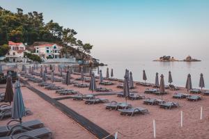 a bunch of chairs and umbrellas on a beach at Hotel AMI Budva Petrovac in Petrovac na Moru