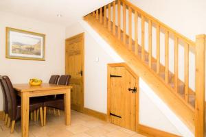 a dining room with a wooden table and a staircase at Piper Cottage, Bilbrough, York in Bilbrough