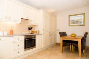 une cuisine avec des placards blancs et une table en bois dans l'établissement Piper Cottage, Bilbrough, York, à Bilbrough